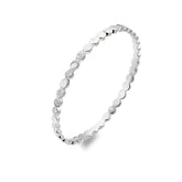 A studio shot of a shiny silver bangle with a repeating pattern of round, flat discs. Some discs are smooth, and others have a hammered texture.
